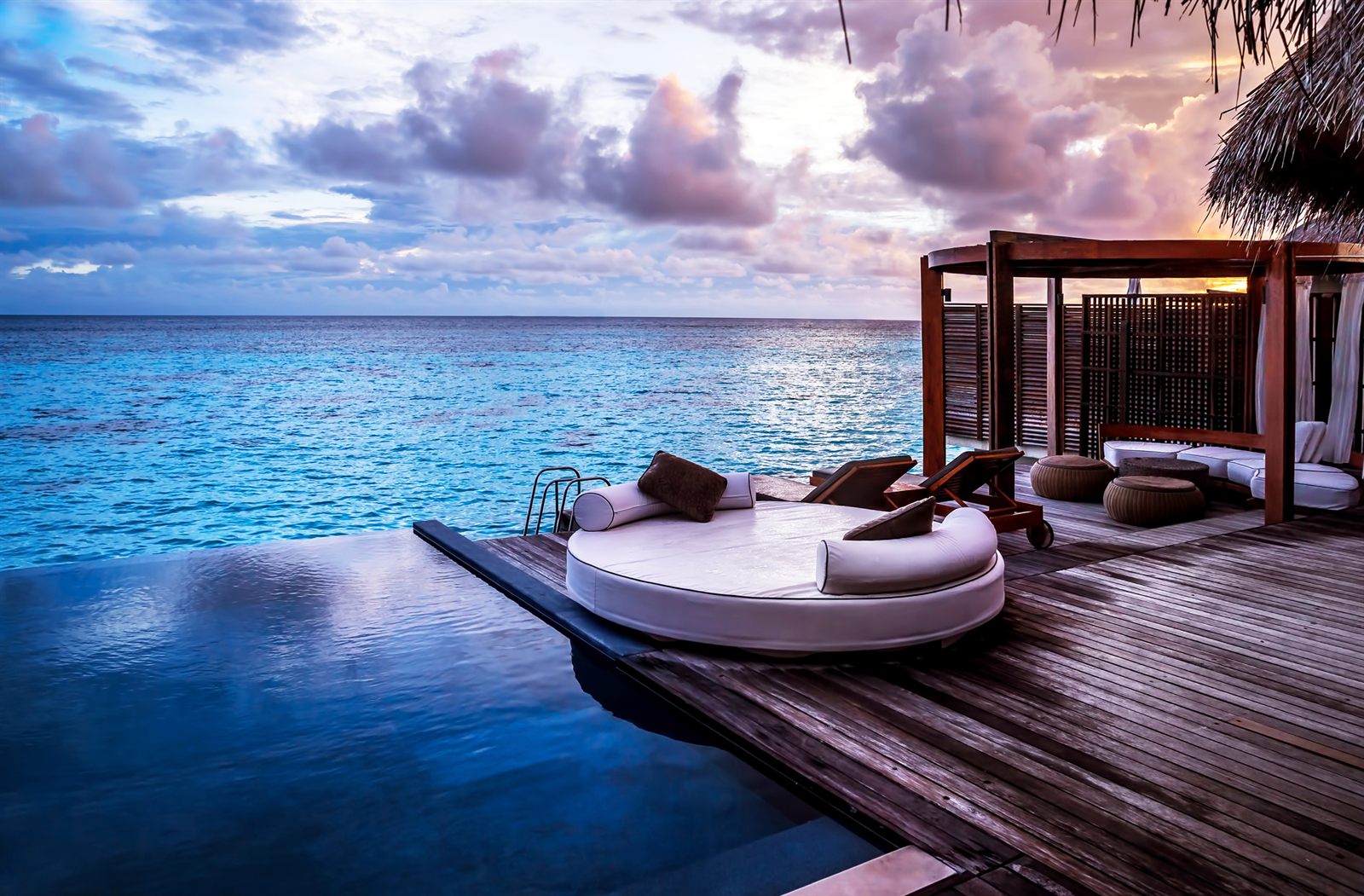 Round daybed on a deck over calm sea at sunset